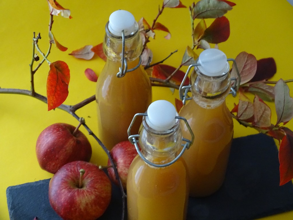 Bottles, of apple juice, apples, branches, black slate