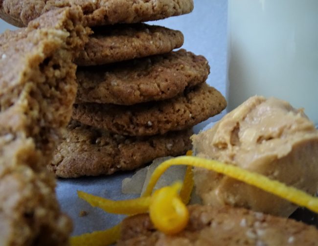 stack of cookies, spoon of peanut butter, milk, orange zest