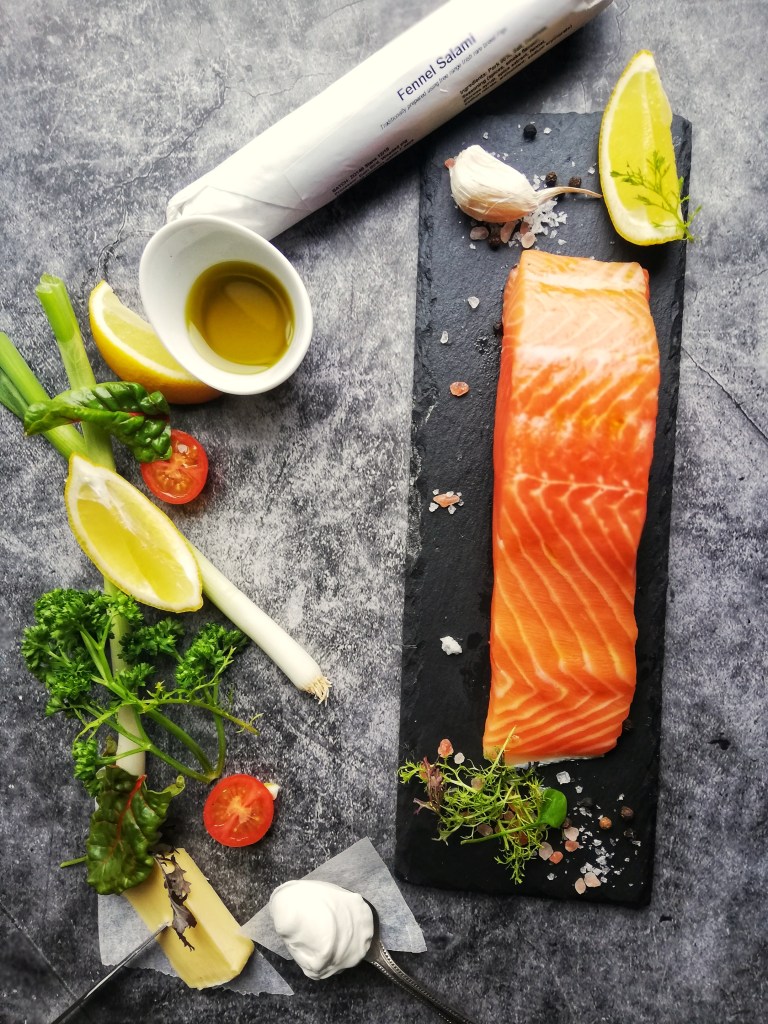 Salmon fillet on slate,parsley sprigs, lemons, fennel salami