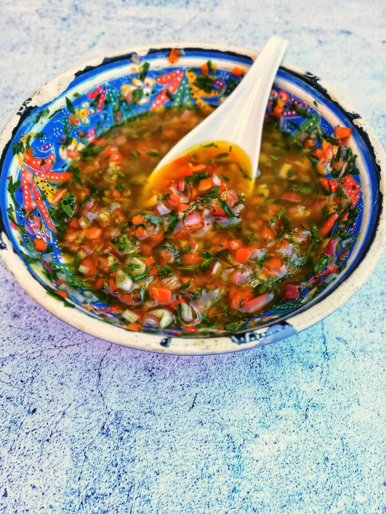 Herb, shallot, sweet pepper & harissa dressing in colourful bowl.