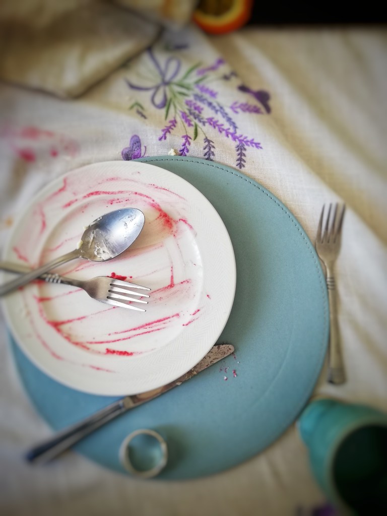 Devoured strawberry and raspberry pavlova, empty plate, cutlery